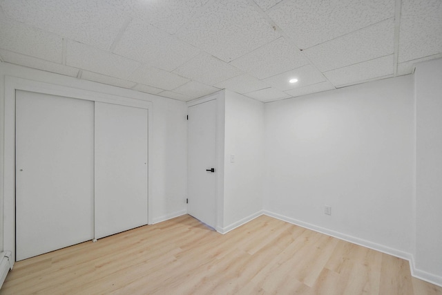 basement with a drop ceiling and light hardwood / wood-style floors