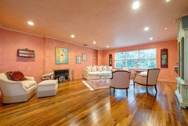 living room featuring crown molding, a brick fireplace, and hardwood / wood-style flooring