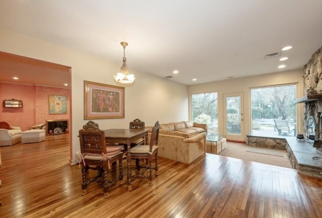 dining room featuring a large fireplace, a notable chandelier, and light wood-type flooring