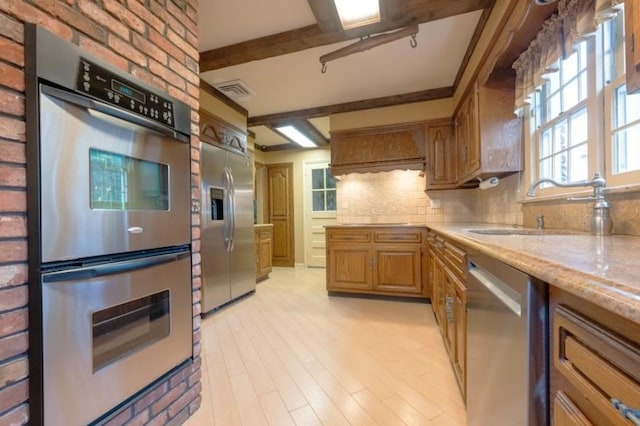 kitchen featuring sink, light hardwood / wood-style flooring, appliances with stainless steel finishes, light stone countertops, and decorative backsplash