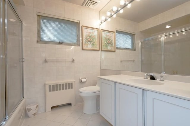 full bathroom featuring tile patterned floors, radiator heating unit, toilet, and tile walls