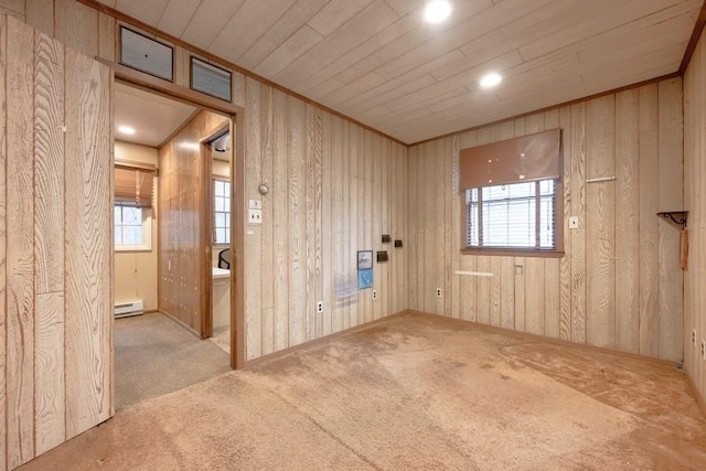 unfurnished room featuring crown molding, wooden walls, light colored carpet, and a healthy amount of sunlight