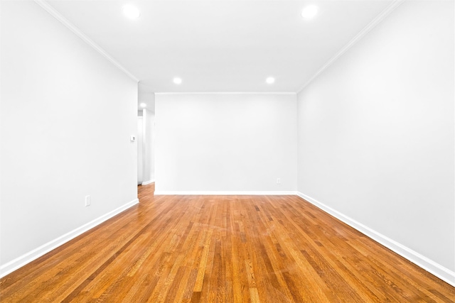 spare room featuring crown molding and light hardwood / wood-style floors