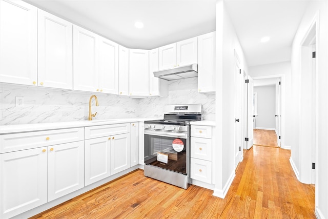 kitchen featuring tasteful backsplash, white cabinetry, sink, gas stove, and light hardwood / wood-style flooring