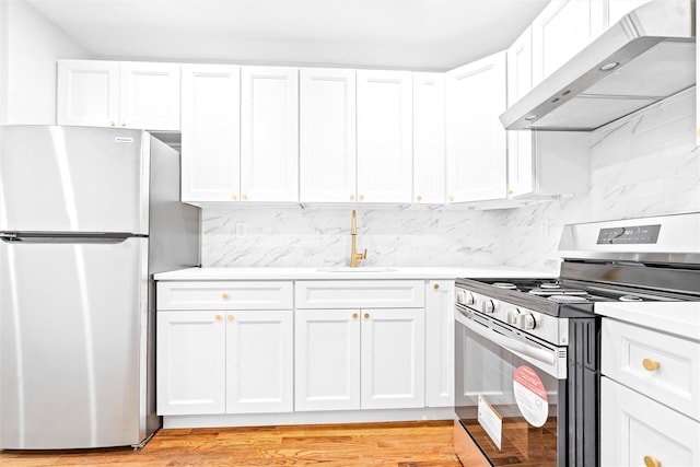 kitchen featuring wall chimney range hood, stainless steel appliances, and white cabinets