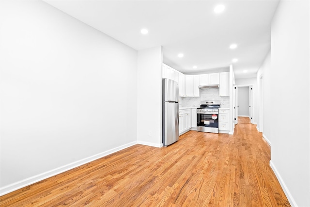 kitchen featuring appliances with stainless steel finishes, white cabinets, light wood-type flooring, and decorative backsplash