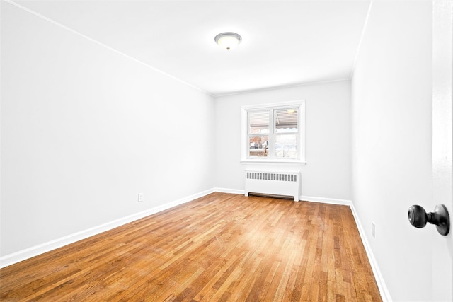 spare room featuring radiator, crown molding, and light hardwood / wood-style floors