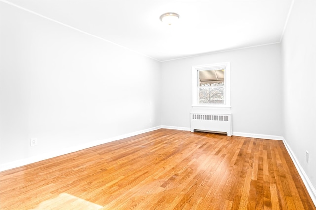 empty room featuring hardwood / wood-style flooring, ornamental molding, and radiator