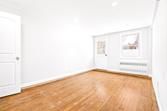 spare room featuring radiator and light hardwood / wood-style floors