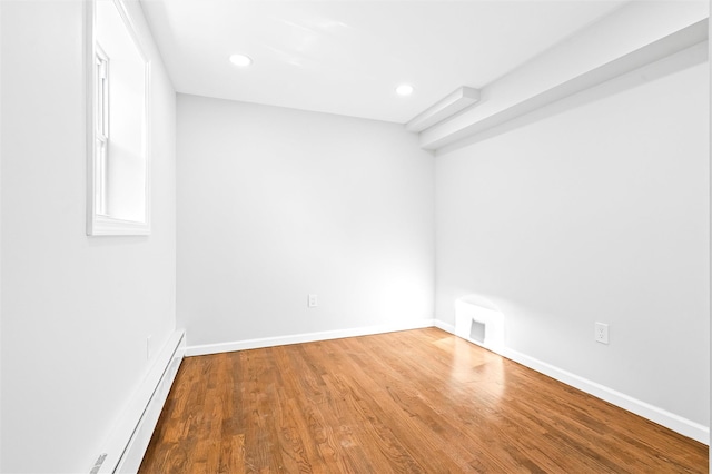 unfurnished room with hardwood / wood-style flooring and baseboard heating