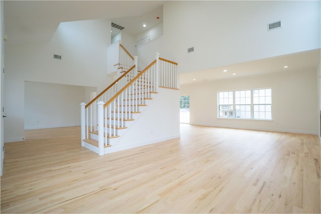 interior space with stairs, wood finished floors, visible vents, and baseboards