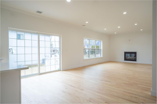 unfurnished living room featuring light wood-type flooring, visible vents, a glass covered fireplace, and recessed lighting