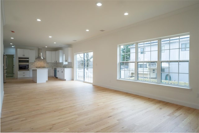 unfurnished living room with recessed lighting, light wood-type flooring, baseboards, and ornamental molding