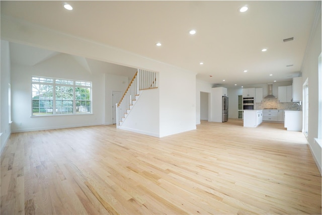 unfurnished living room with stairs, recessed lighting, light wood-type flooring, and a sink