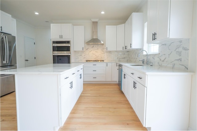 kitchen featuring a center island, crown molding, stainless steel appliances, wall chimney exhaust hood, and a sink