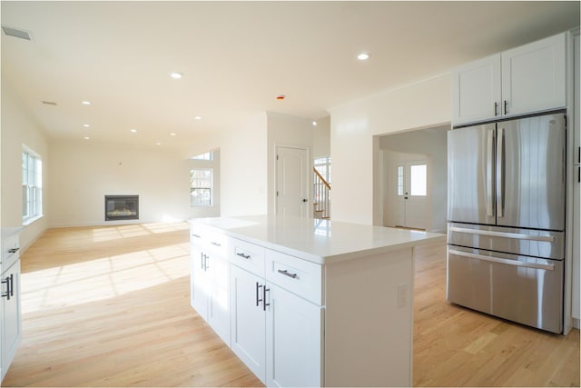 kitchen featuring a glass covered fireplace, visible vents, light wood-type flooring, and freestanding refrigerator