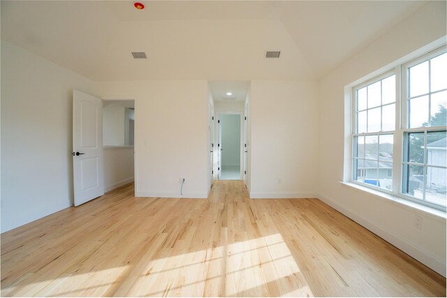 interior space with visible vents, light wood-style flooring, baseboards, and vaulted ceiling