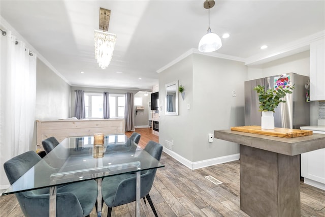 dining area featuring crown molding, hardwood / wood-style floors, and an inviting chandelier