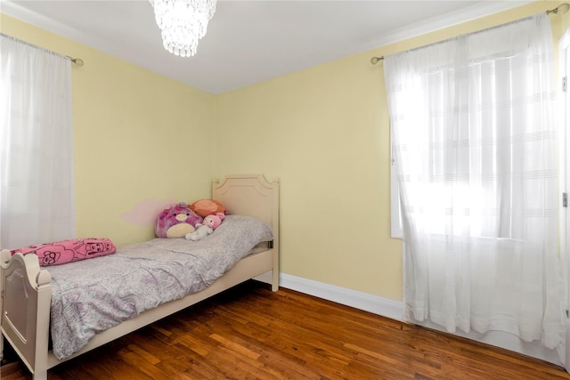 bedroom with dark hardwood / wood-style flooring and a notable chandelier