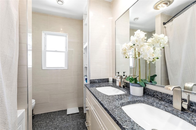 bathroom with vanity, toilet, and tile walls