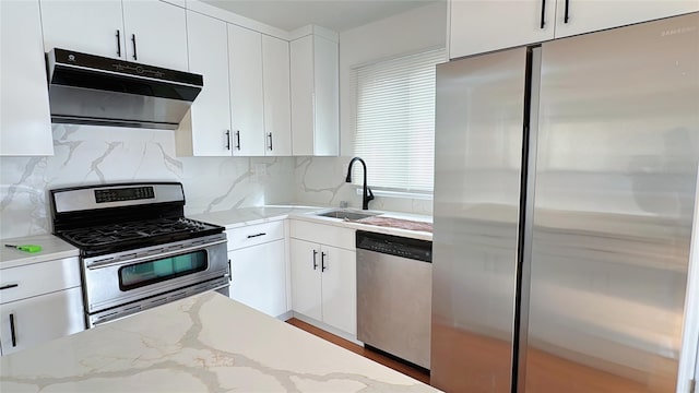 kitchen with light stone countertops, white cabinets, appliances with stainless steel finishes, tasteful backsplash, and sink