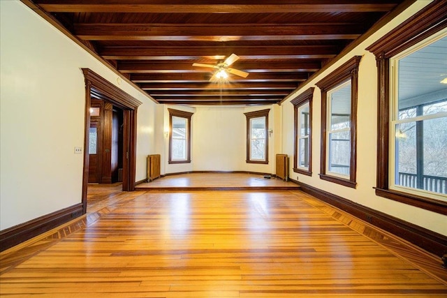 empty room with beamed ceiling, radiator, and a wealth of natural light