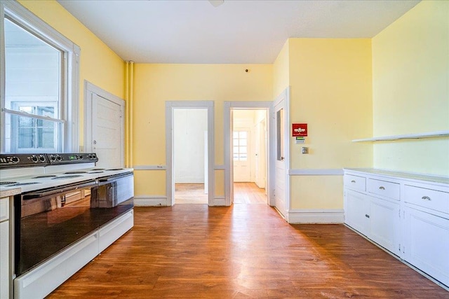 kitchen with white cabinetry, plenty of natural light, wood-type flooring, and electric range