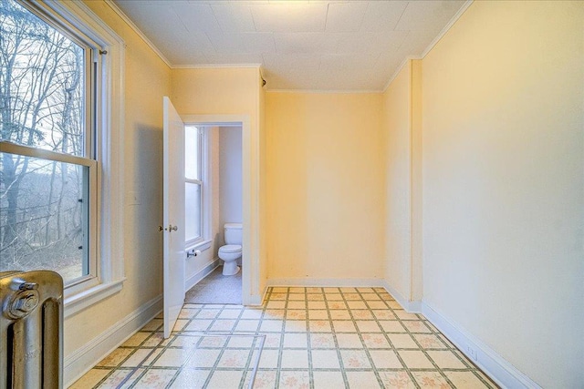 bathroom featuring crown molding, toilet, radiator, and a wealth of natural light