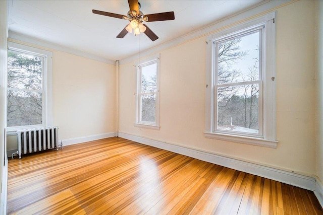 empty room featuring crown molding, ceiling fan, radiator, and light hardwood / wood-style floors