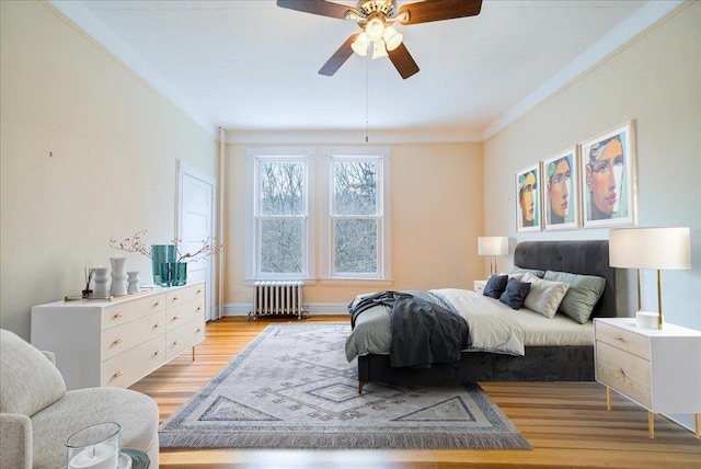 bedroom with crown molding, ceiling fan, radiator heating unit, and light wood-type flooring