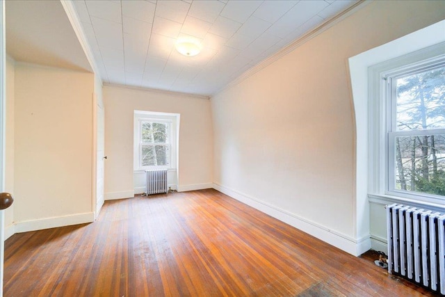 unfurnished room with crown molding, radiator, and hardwood / wood-style floors