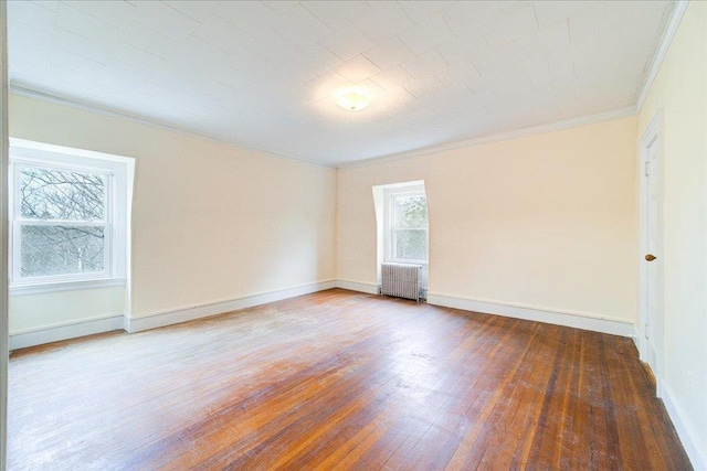 spare room with ornamental molding, radiator, and wood-type flooring