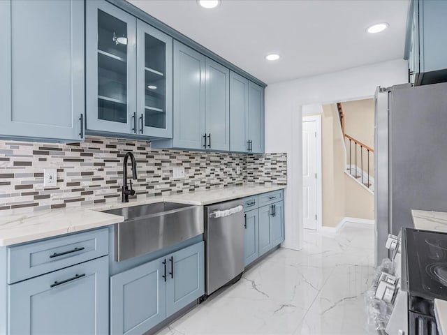 kitchen featuring stainless steel appliances, tasteful backsplash, sink, blue cabinetry, and light stone counters