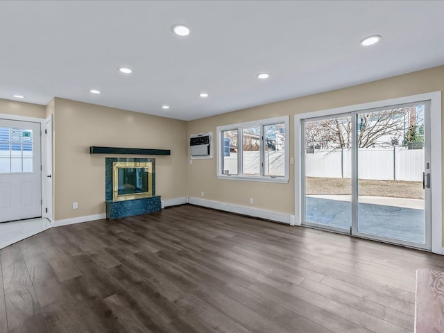 unfurnished living room with a tile fireplace, plenty of natural light, hardwood / wood-style floors, and a wall unit AC