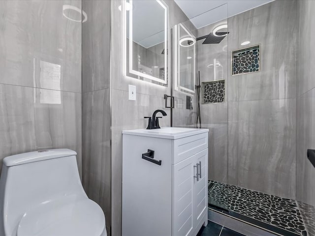 bathroom featuring vanity, toilet, tile walls, and tiled shower