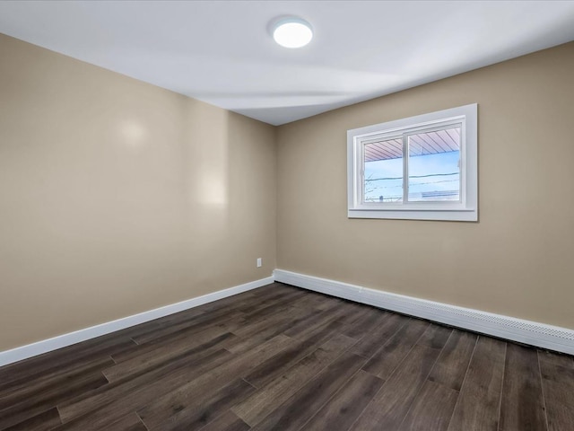 unfurnished room with a baseboard heating unit and dark hardwood / wood-style flooring