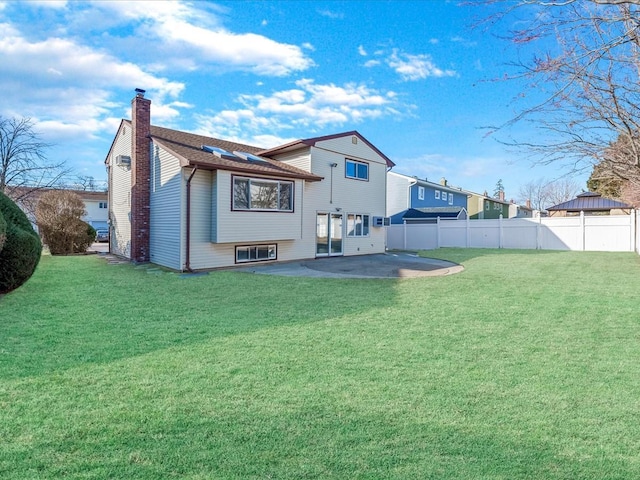 back of house with a patio area and a lawn