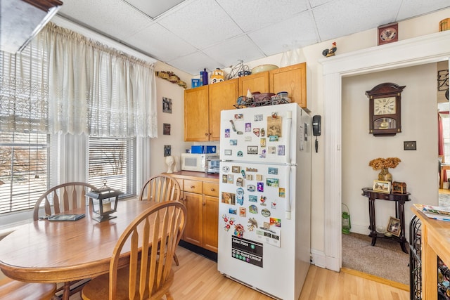 kitchen featuring a drop ceiling, white appliances, and light hardwood / wood-style floors