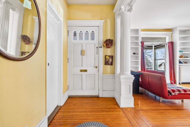 foyer entrance featuring light hardwood / wood-style floors and decorative columns