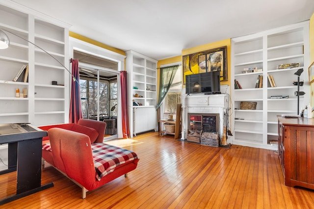 sitting room featuring a fireplace, built in features, and wood-type flooring