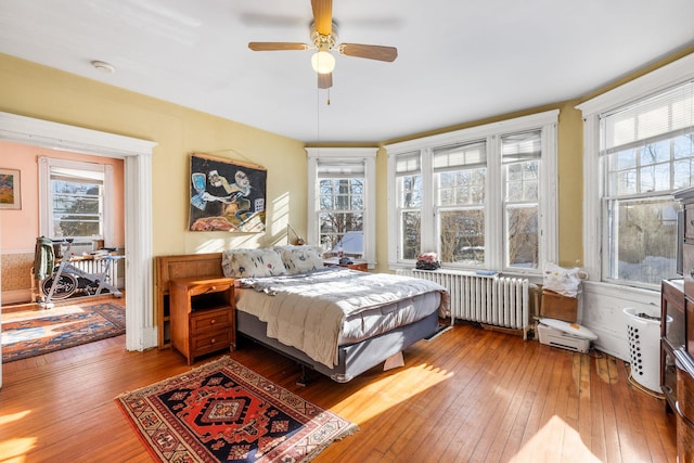 bedroom featuring hardwood / wood-style floors, radiator heating unit, and ceiling fan