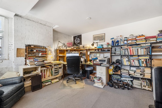 carpeted office space featuring a workshop area and brick wall