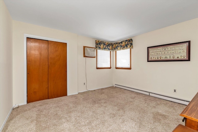 unfurnished bedroom with carpet floors, baseboard heating, and a closet