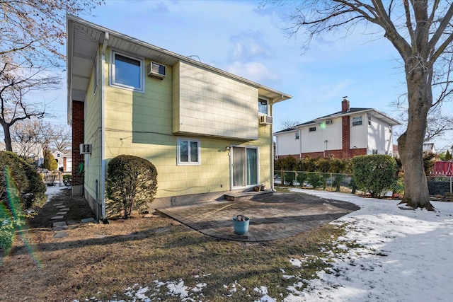 snow covered rear of property with a patio