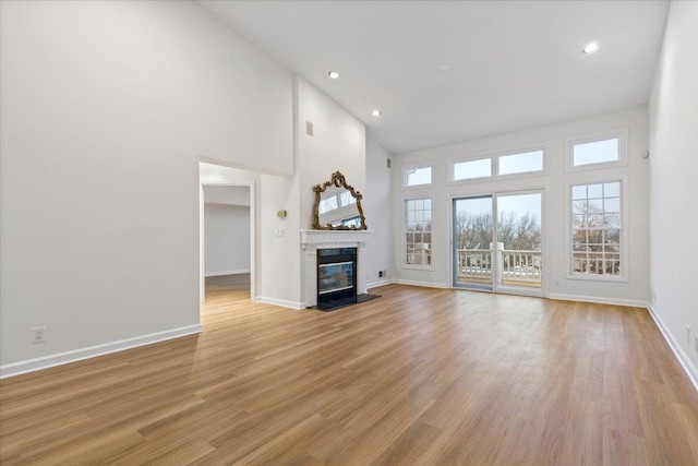 unfurnished living room featuring high vaulted ceiling and light hardwood / wood-style flooring