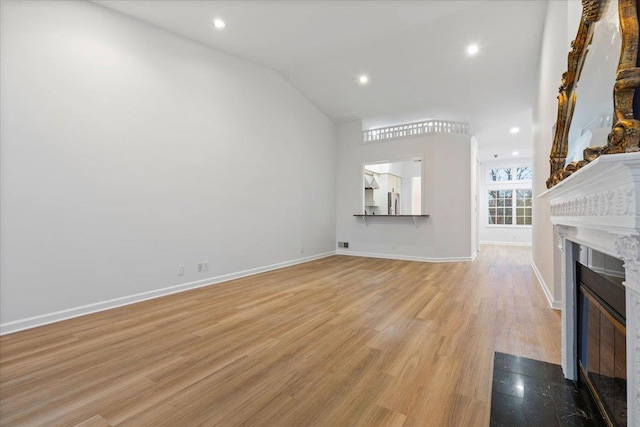 unfurnished living room featuring vaulted ceiling and light hardwood / wood-style floors