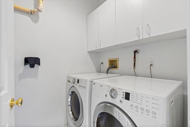 laundry area with washer and clothes dryer and cabinets