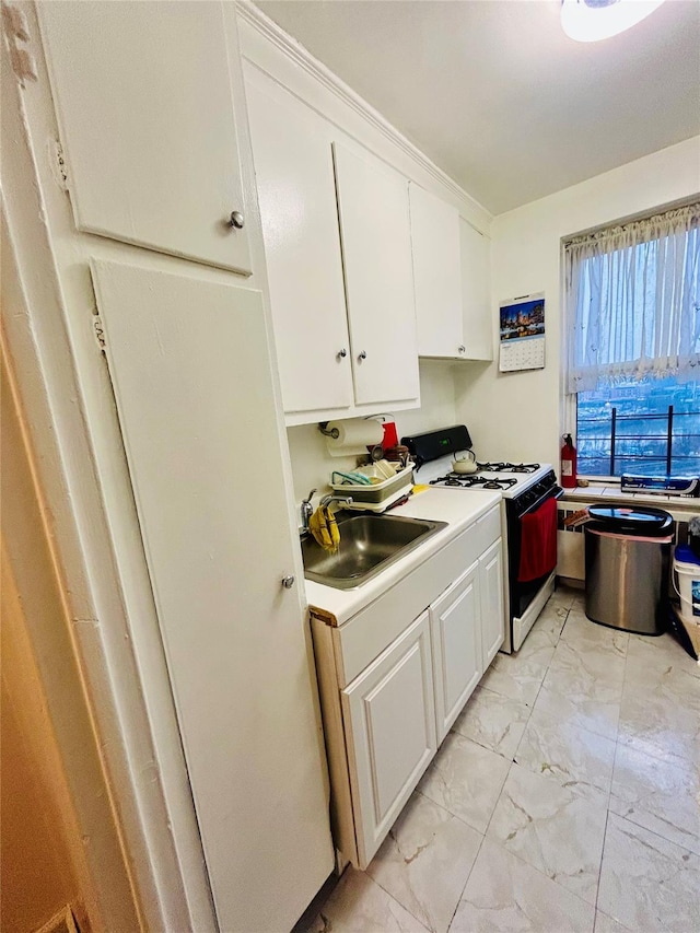 kitchen featuring sink, white range with gas stovetop, and white cabinets