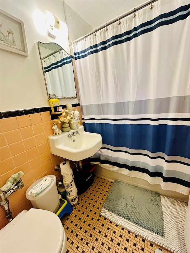 bathroom featuring walk in shower, tile patterned floors, toilet, sink, and tile walls