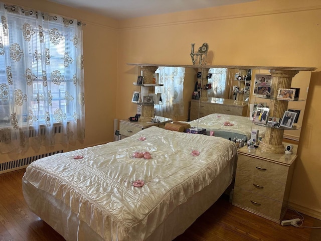 bedroom with radiator, dark wood-type flooring, and multiple windows